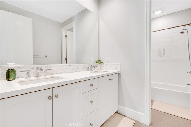 bathroom featuring a sink, baseboards, shower / tub combination, and double vanity