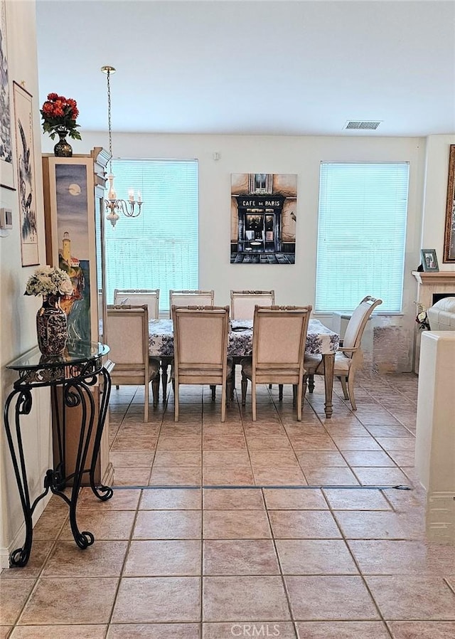 dining area with light tile patterned floors, visible vents, plenty of natural light, and an inviting chandelier