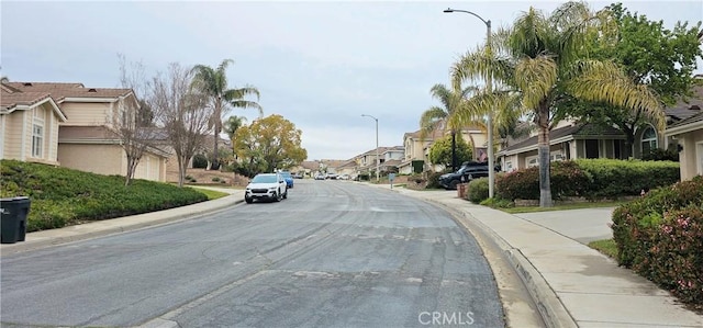 view of road with a residential view, curbs, street lights, and sidewalks