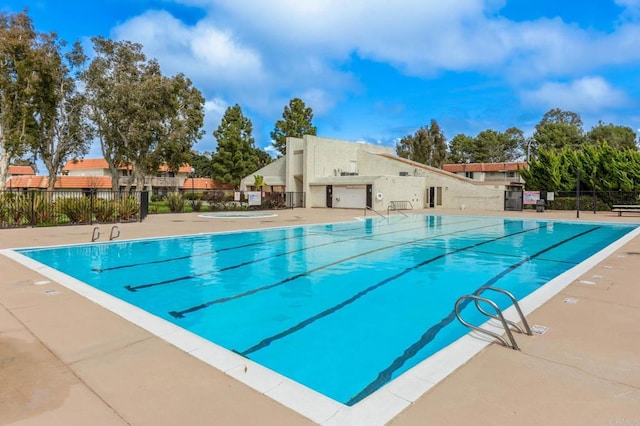 community pool with a patio and fence