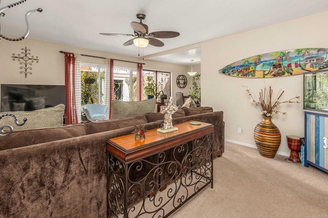 living room with ceiling fan, baseboards, and light carpet