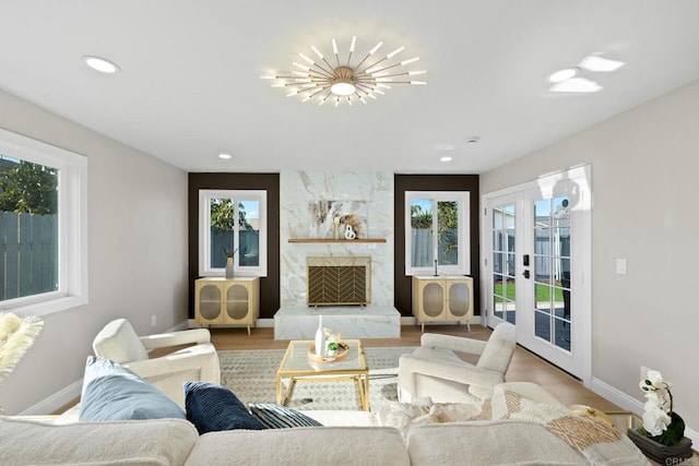 living area with a large fireplace, baseboards, recessed lighting, french doors, and wood finished floors