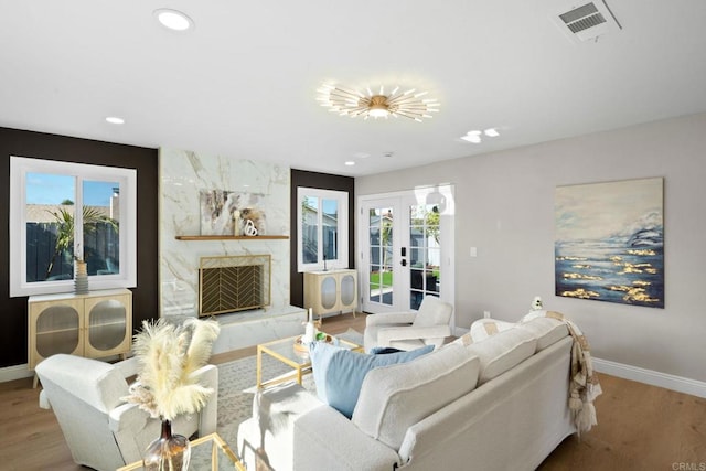 living room featuring visible vents, wood finished floors, a high end fireplace, french doors, and baseboards