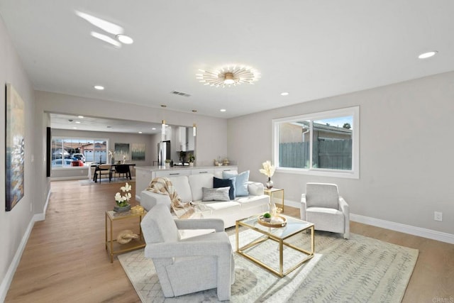 living area with baseboards, visible vents, and light wood-type flooring