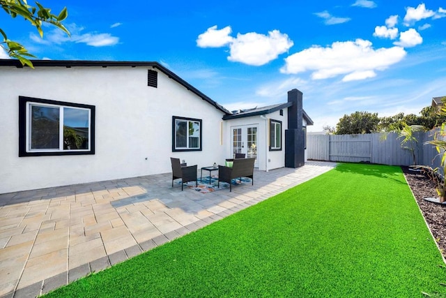 back of house featuring stucco siding, french doors, a yard, fence private yard, and a patio area