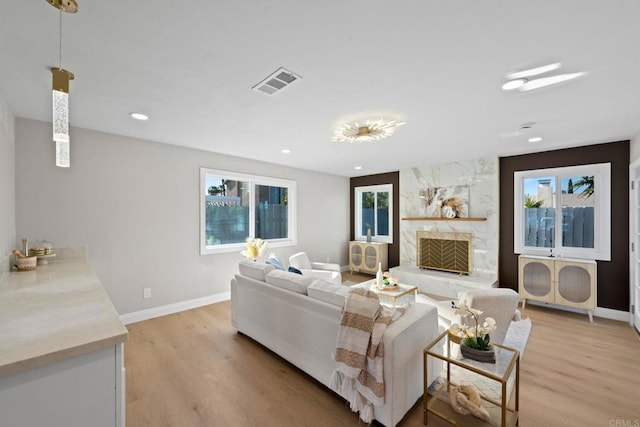 living room with visible vents, a high end fireplace, recessed lighting, light wood finished floors, and baseboards