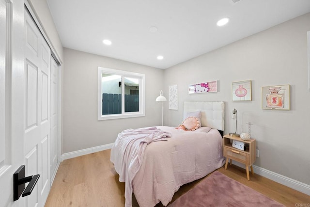 bedroom featuring a closet, recessed lighting, baseboards, and light wood finished floors