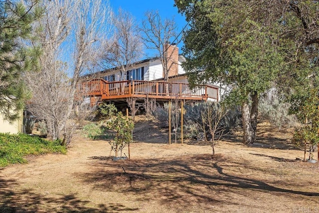 rear view of property with a wooden deck and a chimney