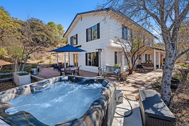 rear view of property featuring a patio area and a hot tub