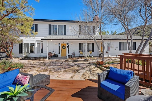 rear view of property with a deck, an outdoor living space, and a chimney