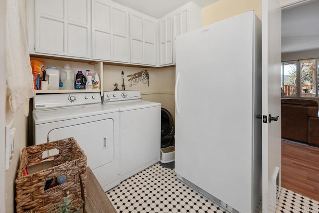 clothes washing area featuring cabinet space, light floors, and washing machine and clothes dryer