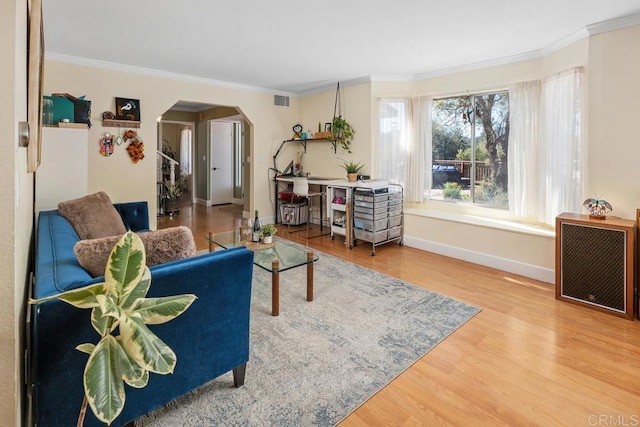 living room featuring arched walkways, visible vents, crown molding, and wood finished floors