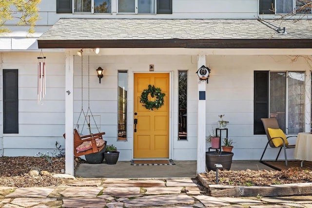 entrance to property with covered porch and roof with shingles