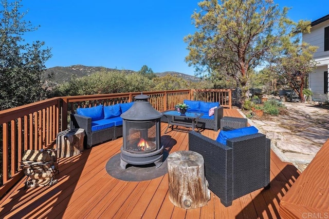 deck featuring a mountain view and an outdoor living space with a fire pit