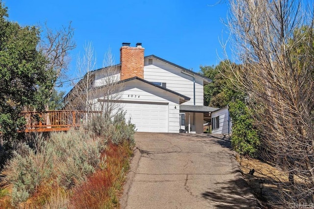 view of side of home with an attached garage, driveway, and a chimney