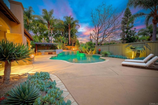 pool at dusk featuring a fenced backyard, a fenced in pool, and a patio