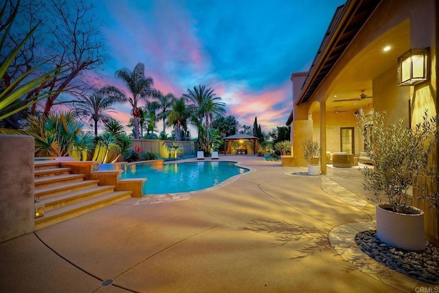 pool at dusk with a patio, fence, a ceiling fan, a fenced in pool, and a gazebo