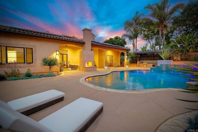 pool at dusk featuring an outdoor pool and a patio