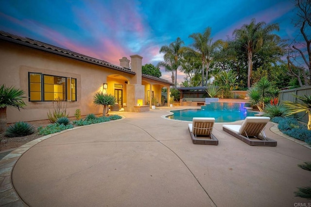 pool at dusk with a patio area, a fenced in pool, and a fenced backyard