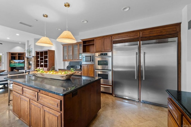 kitchen featuring visible vents, pendant lighting, brown cabinetry, built in appliances, and a warming drawer