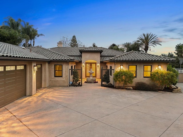 mediterranean / spanish home with fence, a tile roof, stucco siding, a chimney, and driveway