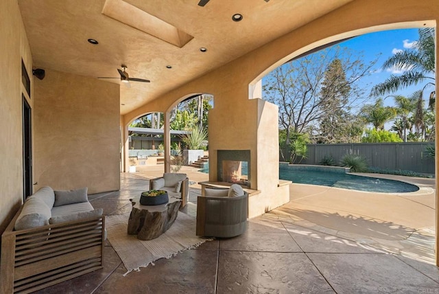 view of patio featuring fence, a fenced in pool, an outdoor living space with a fireplace, and ceiling fan