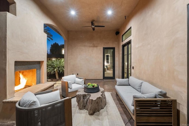 view of patio with an outdoor living space with a fireplace and ceiling fan