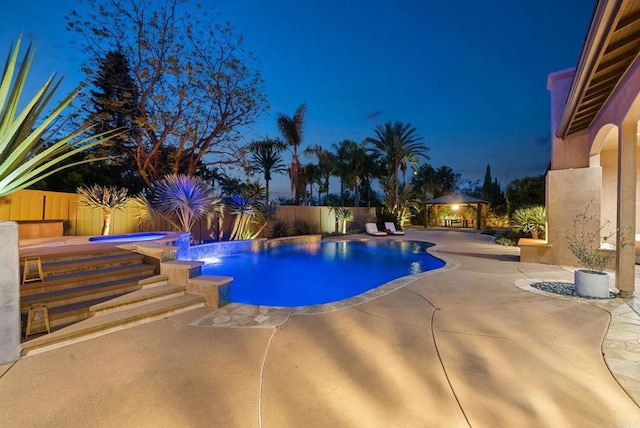 pool at night featuring a fenced in pool, a patio, an in ground hot tub, and a fenced backyard