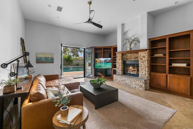 living area featuring visible vents, a ceiling fan, and a stone fireplace
