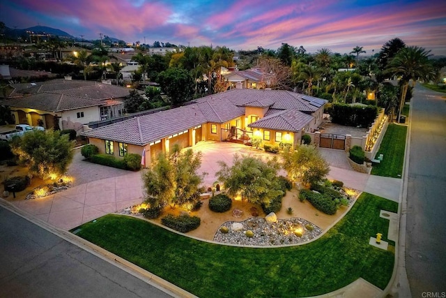 view of front of property with a tiled roof, an attached garage, curved driveway, and a gate