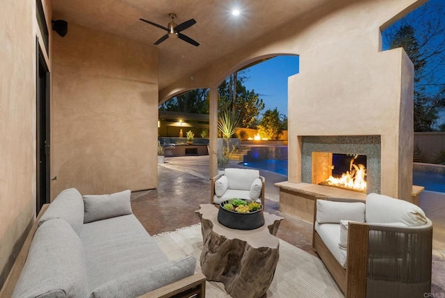 view of patio / terrace with an outdoor living space with a fireplace, ceiling fan, and an outdoor pool