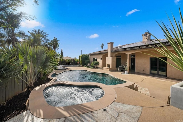 outdoor pool with an in ground hot tub and a patio area