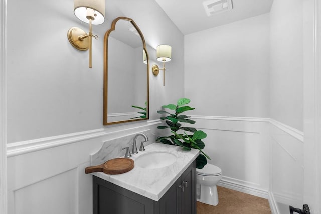 bathroom featuring visible vents, wainscoting, toilet, and vanity