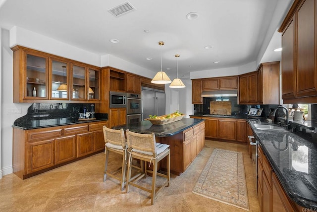 kitchen with visible vents, a center island, a sink, built in appliances, and under cabinet range hood