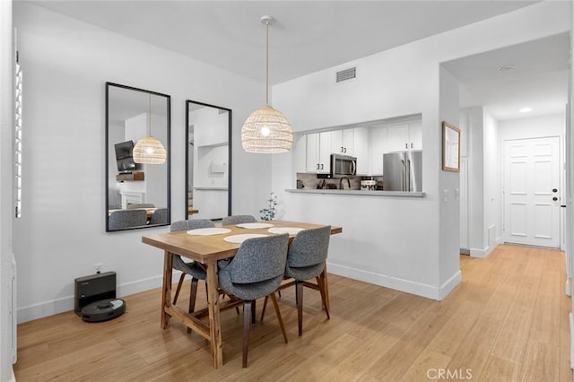 dining area with baseboards, visible vents, and light wood finished floors