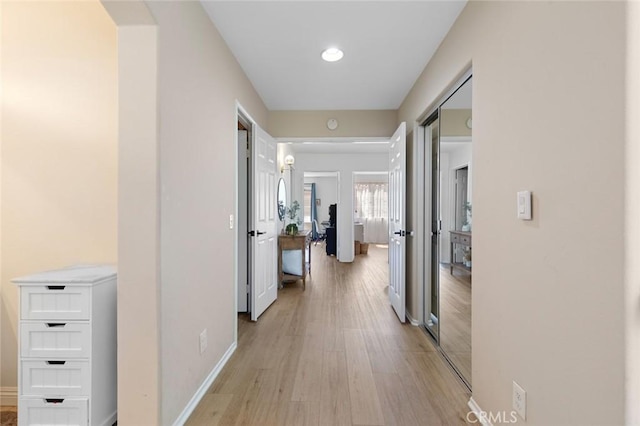 hallway featuring baseboards and light wood finished floors