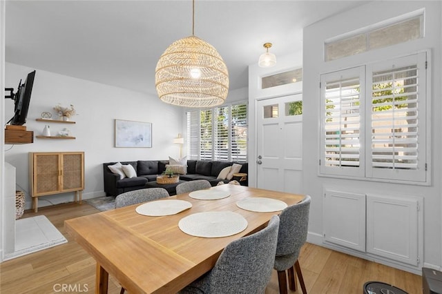 dining space with baseboards and light wood-style flooring