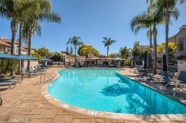 community pool with a patio and fence