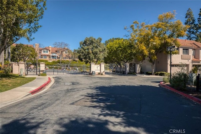 view of street featuring a gate, curbs, sidewalks, and a gated entry