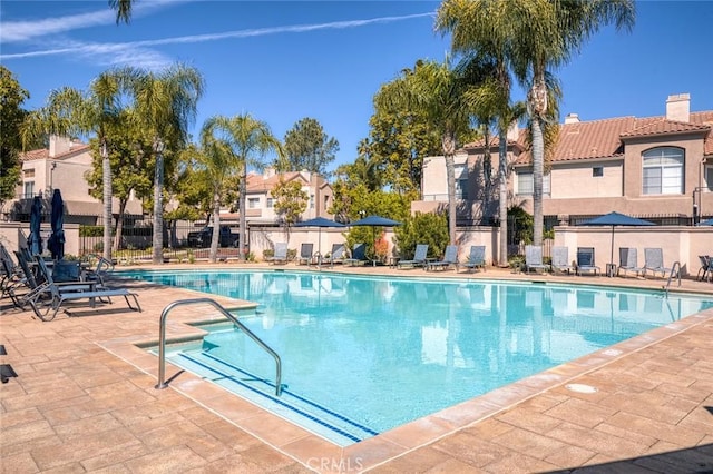 community pool featuring a residential view, a patio, and fence