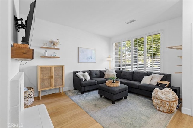 living room featuring visible vents, baseboards, and wood finished floors