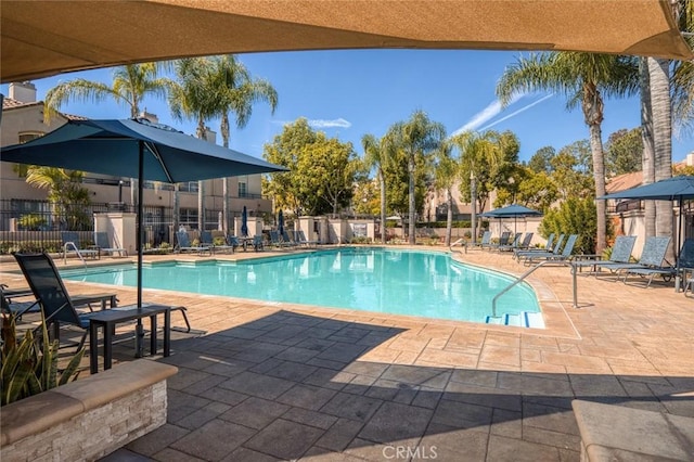 community pool with a patio and fence