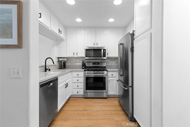 kitchen with a sink, stainless steel appliances, white cabinets, and light countertops