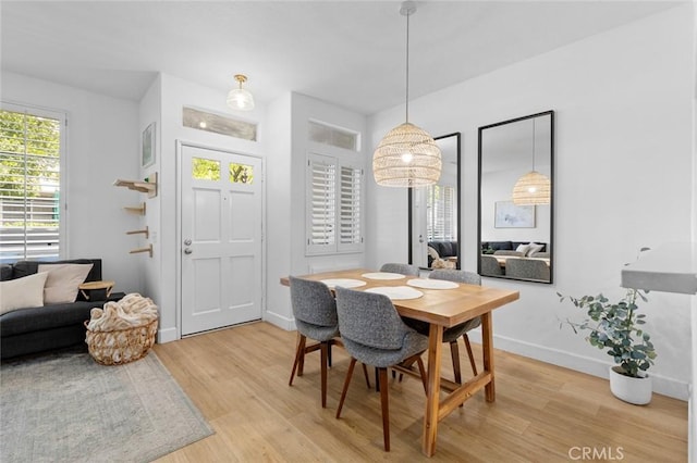 dining space featuring baseboards and light wood-type flooring