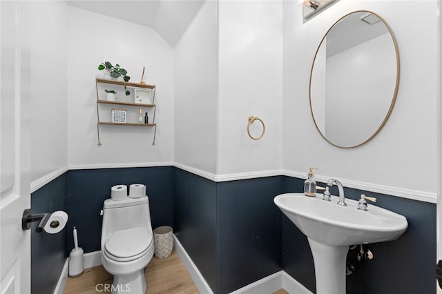 bathroom featuring baseboards, lofted ceiling, toilet, and wood finished floors