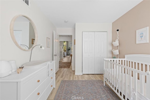 bedroom with a closet, visible vents, and light wood-type flooring