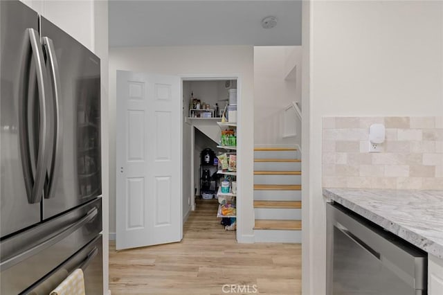 interior space featuring backsplash, light stone countertops, wine cooler, freestanding refrigerator, and light wood-style floors