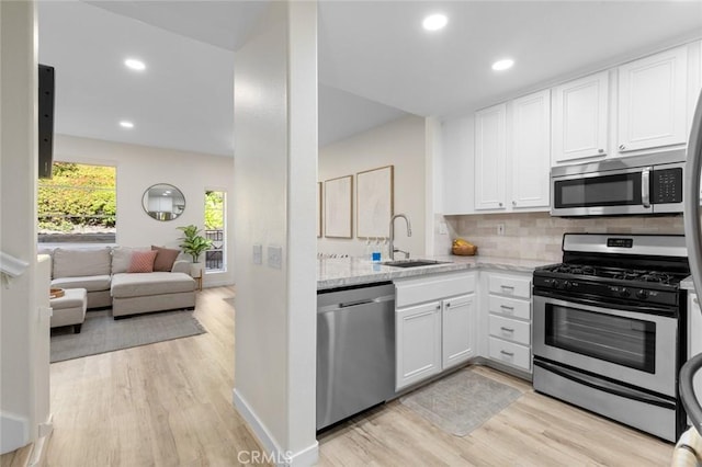 kitchen with a sink, stainless steel appliances, tasteful backsplash, and white cabinetry