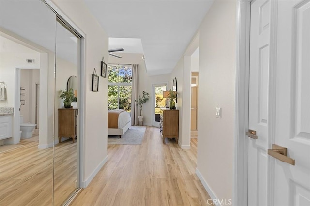 hall with visible vents, baseboards, and light wood-style floors