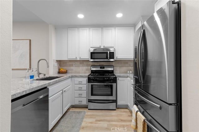 kitchen featuring a sink, appliances with stainless steel finishes, white cabinets, and light wood finished floors